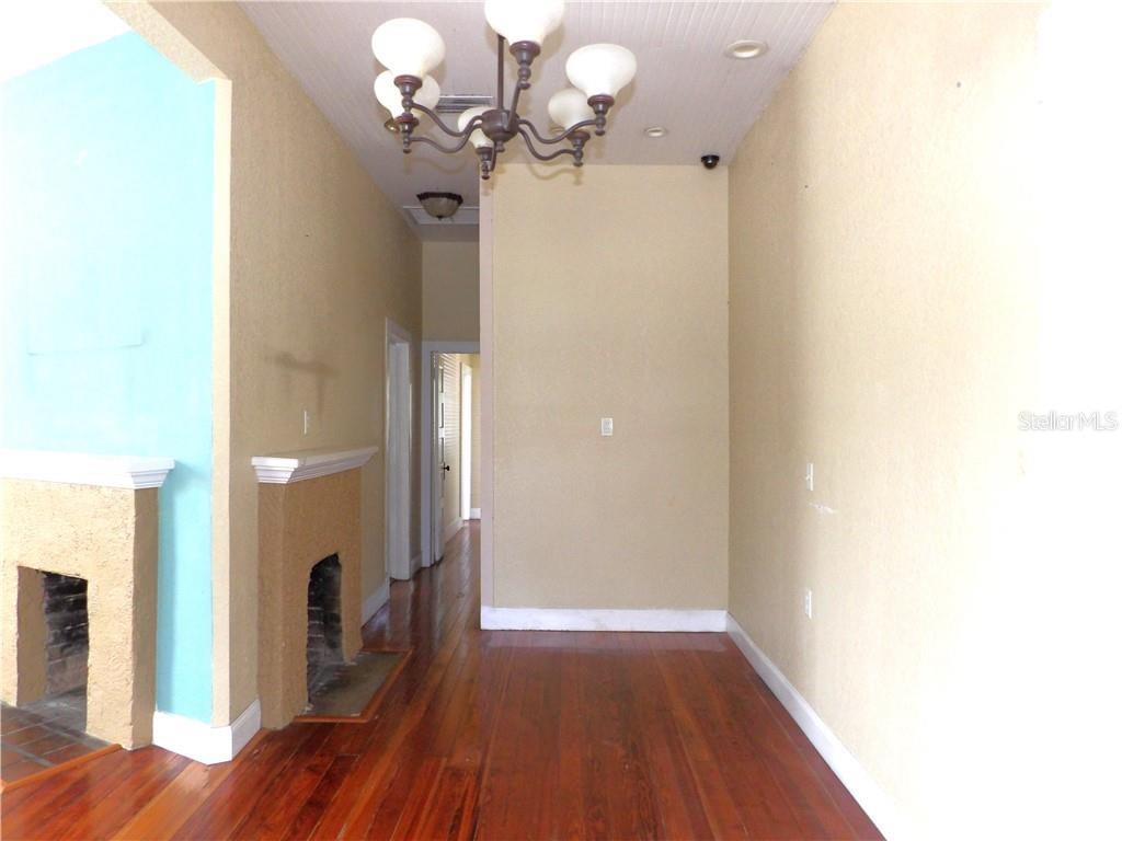 A room with hardwood floors, a fireplace, and a chandelier under a high ceiling — 401 TOMPKINS STREET, INVERNESS, FL