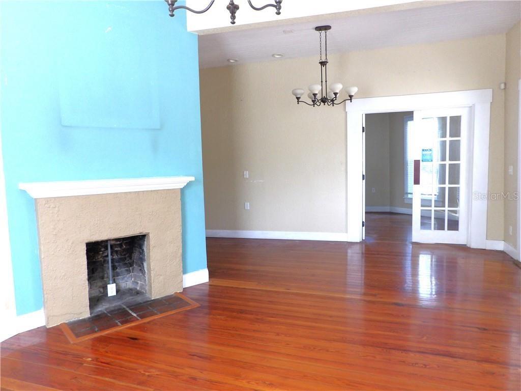 A room with hardwood floors, a blue fireplace, and a white French door — 401 TOMPKINS STREET, INVERNESS, FL