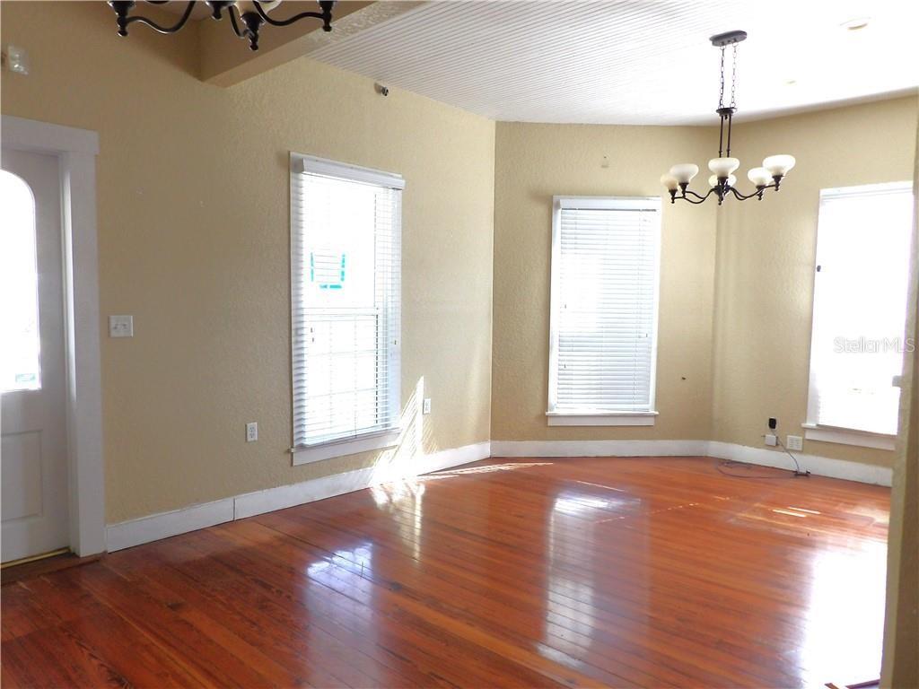 A room with hardwood floors, tan walls, three windows, and a hanging light fixture — 401 TOMPKINS STREET, INVERNESS, FL