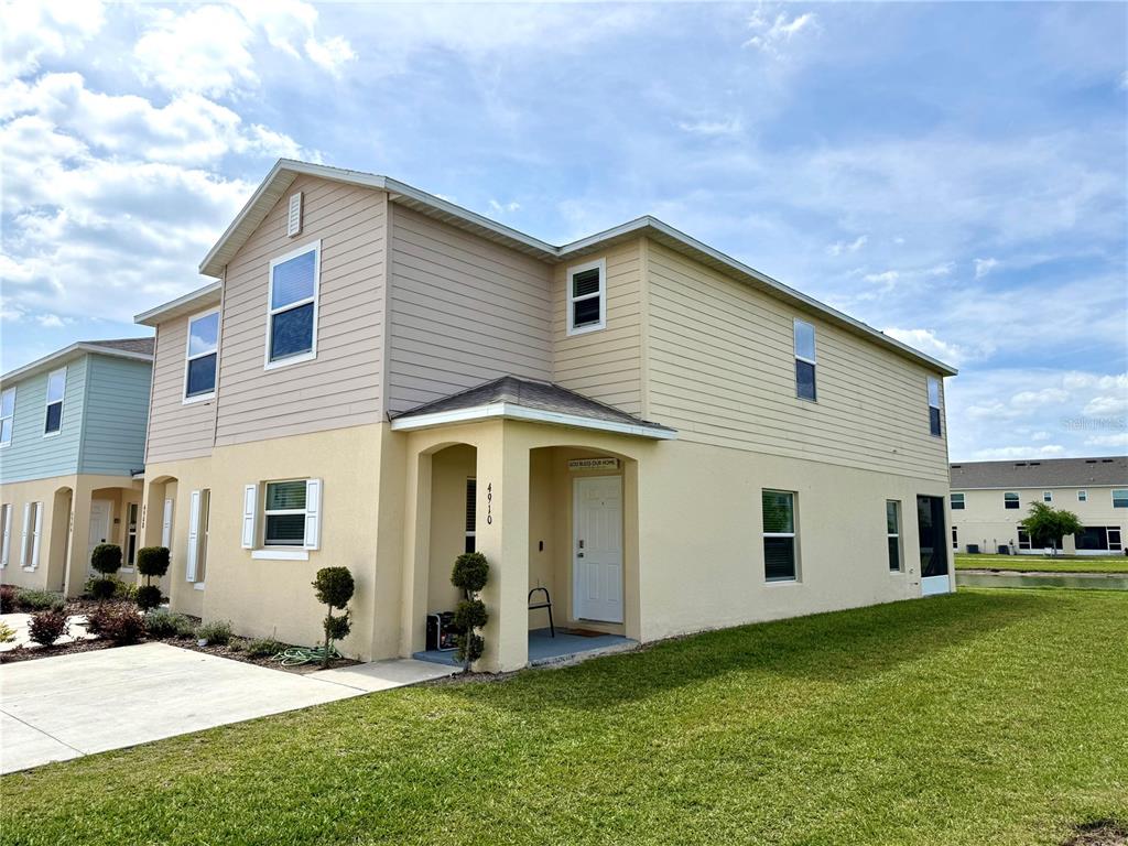 A two-story townhouse with yellow stucco and tan siding features a covered front entrance — 4910 CORAL CASTLE DRIVE, KISSIMMEE, FL