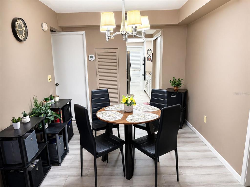 A dining area features a round wooden table, four black chairs, and light wood flooring — 5810 21ST STREET N UNIT 2, ST PETERSBURG, FL