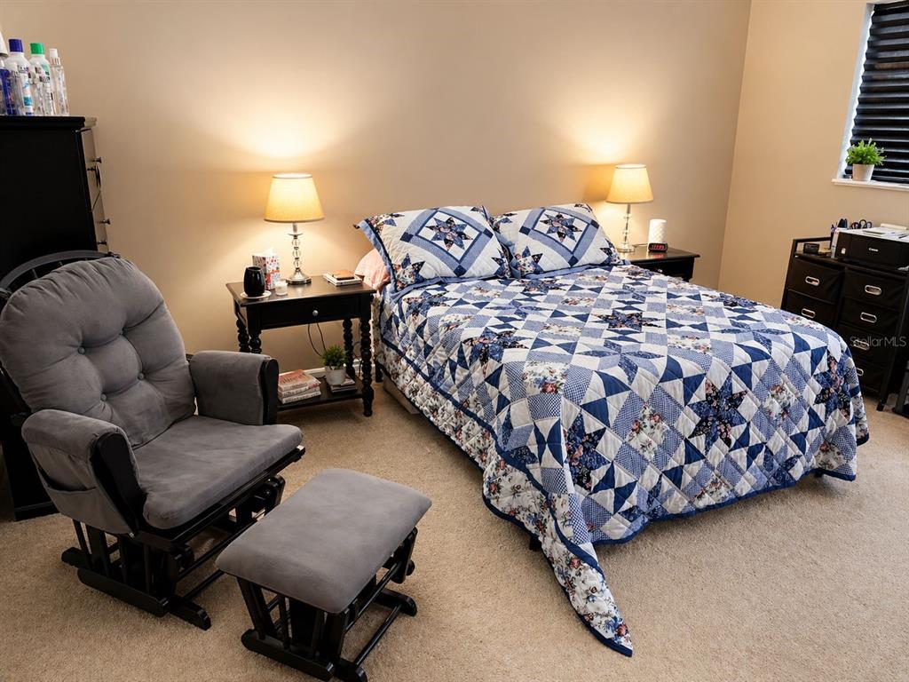 A bedroom features a bed with a blue and white quilt, a matching rocking chair, and nightstands — 5810 21ST STREET N UNIT 2, ST PETERSBURG, FL