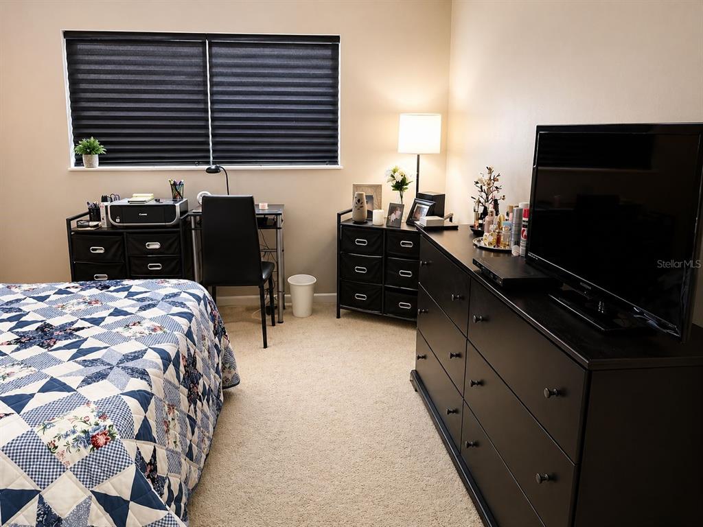 A bedroom features a bed with a quilt, a desk, and a black dresser — 5810 21ST STREET N UNIT 2, ST PETERSBURG, FL