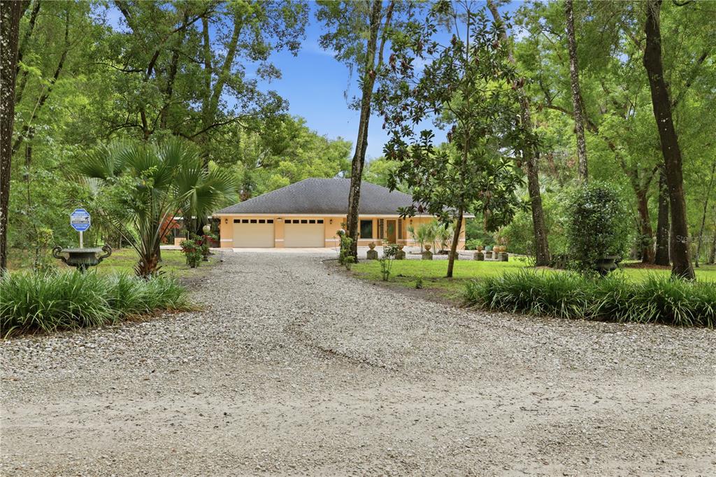 A single-story house with a two-car garage sits at the end of a gravel driveway — 1610 STRATHCONA AVENUE, DELAND, FL