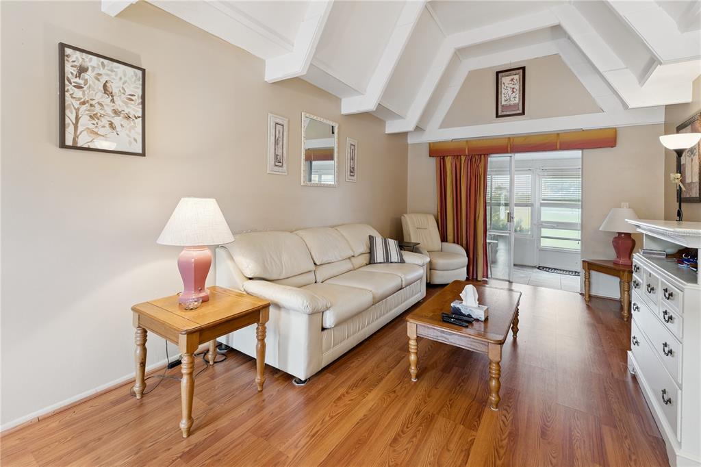 A living room features a white sofa, wood flooring, and a vaulted ceiling with beams — 3821 CLUB CIRCLE, LAKE WALES, FL