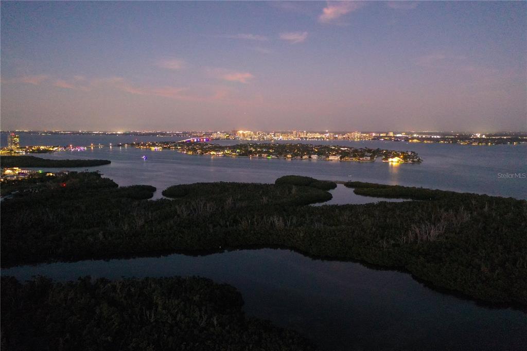 An aerial view of a coastal landscape at twilight with a distant city skyline — 1750 BENJAMIN FRANKLIN DRIVE UNIT 9F, SARASOTA, FL