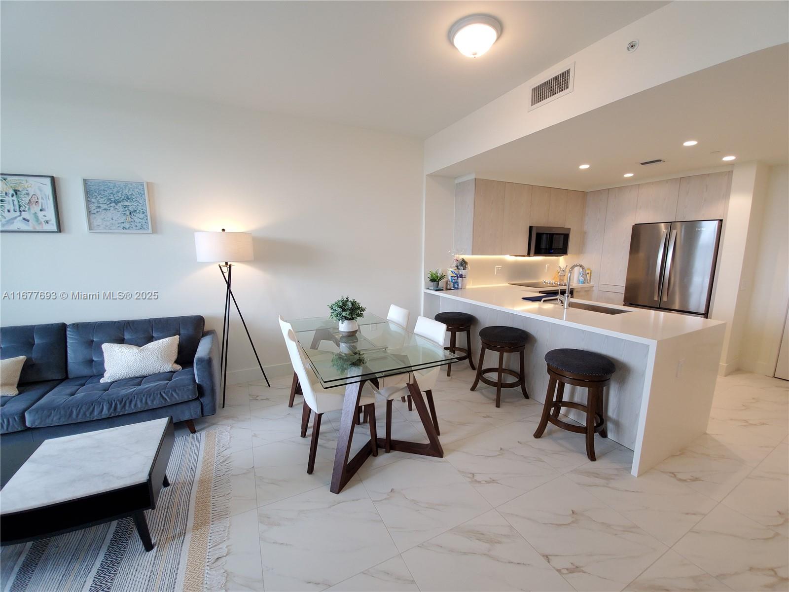 An open-concept living and dining area features a modern kitchen with stainless steel appliances — 2000 Metropica Way # 305, Sunrise FL 33323, SUNRISE, FL