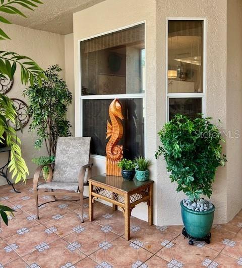 A covered patio features a chair, a side table with a seahorse statue, and potted plants — 9611 CASTLE POINT DRIVE UNIT 916, SARASOTA, FL