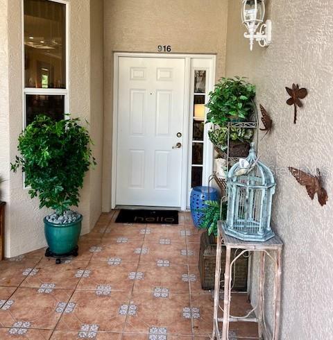 A covered entryway features a white front door, tiled flooring, and potted plants — 9611 CASTLE POINT DRIVE UNIT 916, SARASOTA, FL