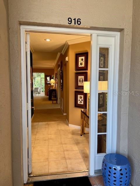 An open doorway reveals a tiled entryway leading to a hallway with framed wall art — 9611 CASTLE POINT DRIVE UNIT 916, SARASOTA, FL