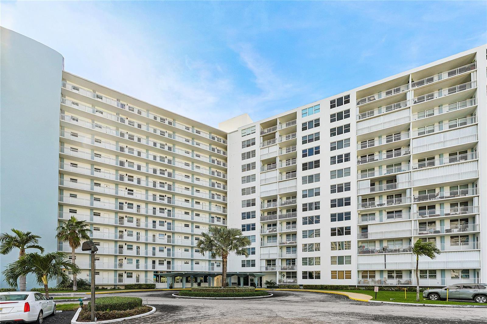A multi-story residential building with white balconies and a circular driveway with palm trees — 201 N Ocean Boulevard # 208, Pompano Beach FL 33062, POMPANO BEACH, FL