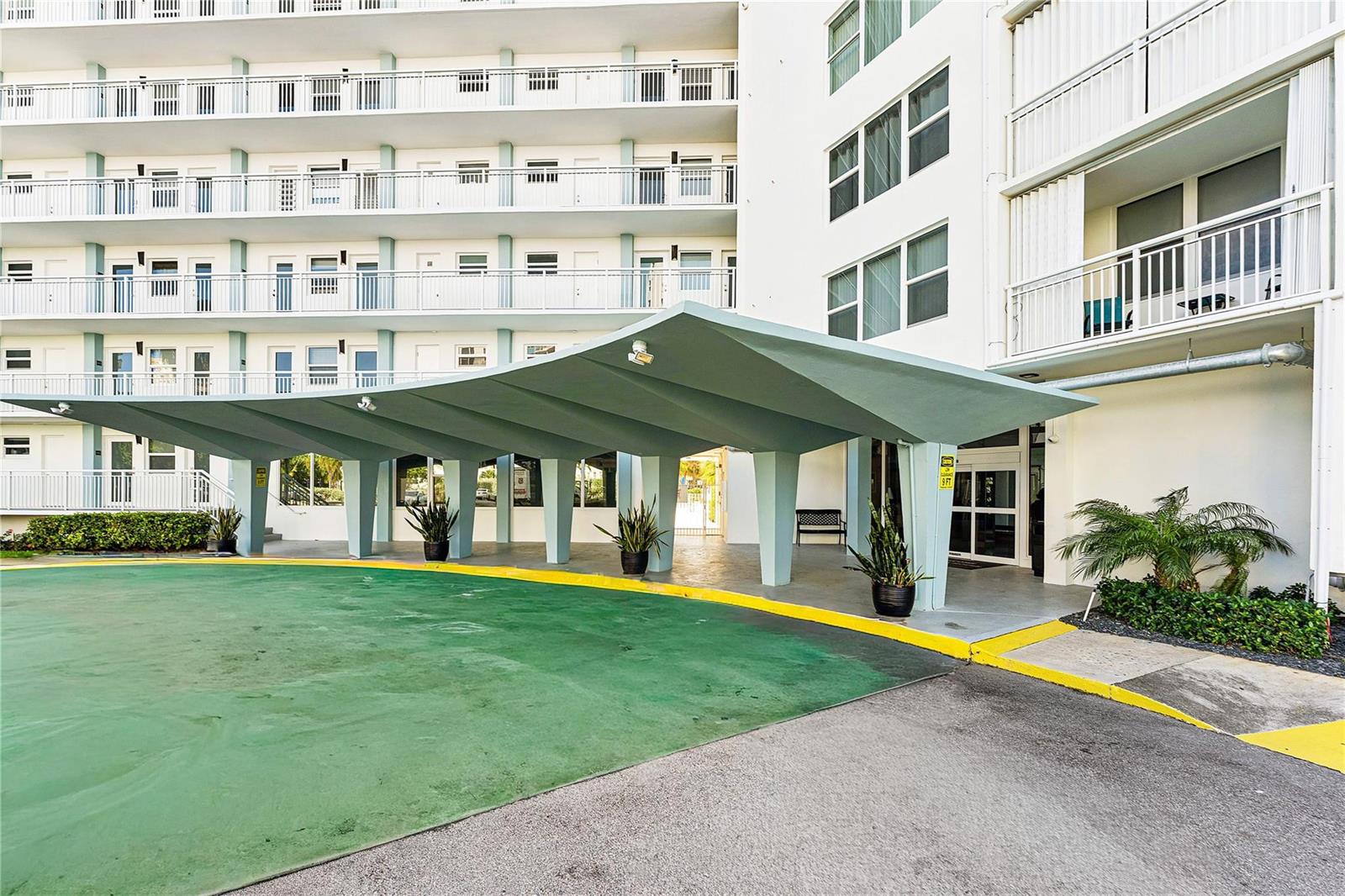 An exterior view of a multi-story apartment building with a large, covered concrete entryway — 201 N Ocean Boulevard # 208, Pompano Beach FL 33062, POMPANO BEACH, FL