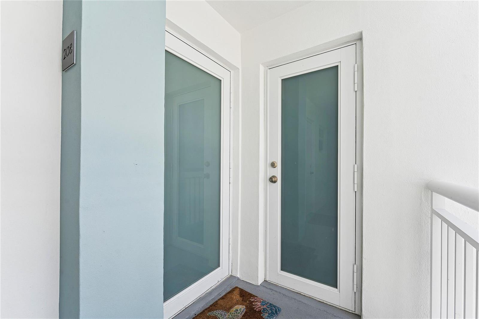 Two white doors with frosted glass panels are set against a light blue and white wall — 201 N Ocean Boulevard # 208, Pompano Beach FL 33062, POMPANO BEACH, FL