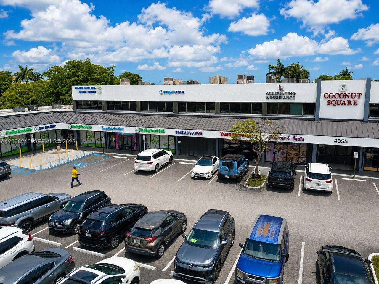 An aerial view of a commercial strip mall parking lot with various storefronts and parked cars — 4355 W 16th Ave, Hialeah FL 33012, HIALEAH, FL