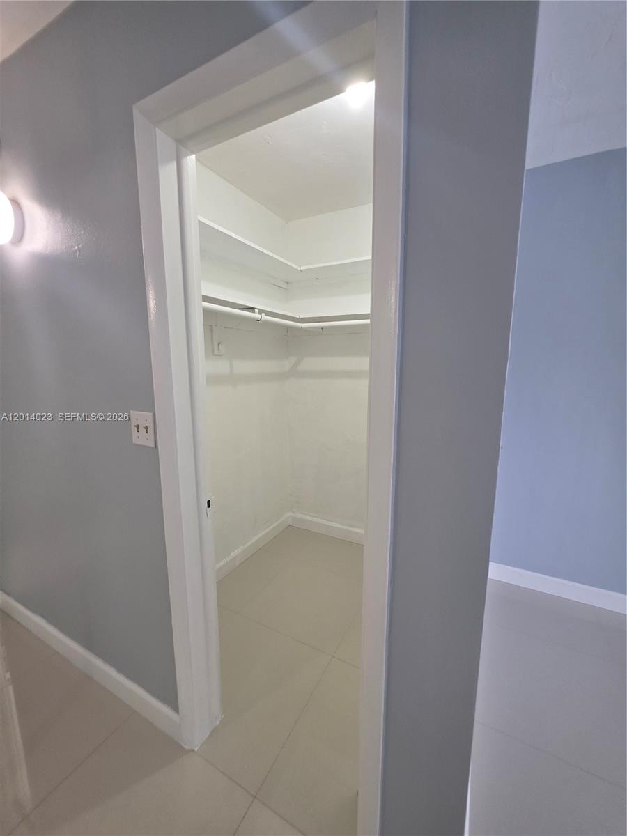 A small walk-in closet features white shelving, a hanging rod, and light-colored tile flooring — 19080 NE 3rd Ct # 314, Miami FL 33179, MIAMI, FL