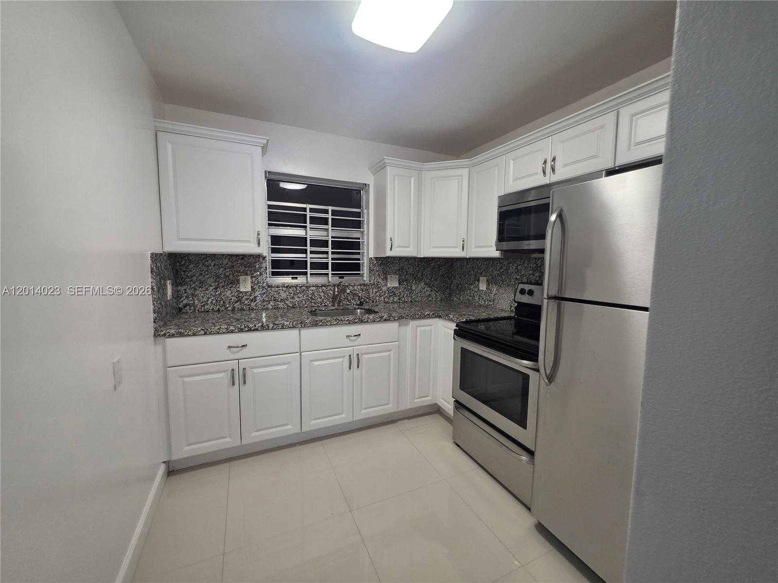 A kitchen features white cabinets, granite countertops, stainless steel appliances, and light tile flooring — 19080 NE 3rd Ct # 314, Miami FL 33179, MIAMI, FL