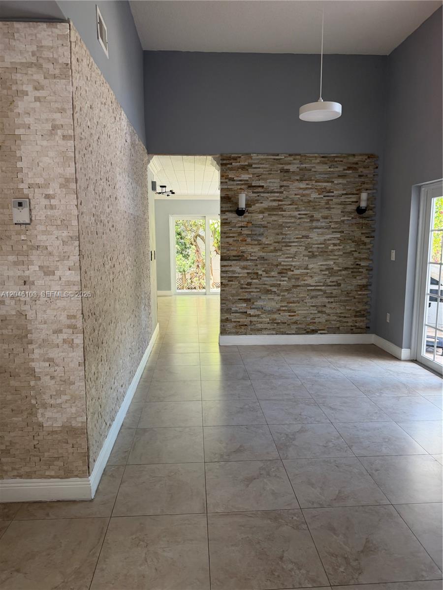 A room features tiled floors, gray walls, and two accent walls covered in stacked stone — MIAMI, FL