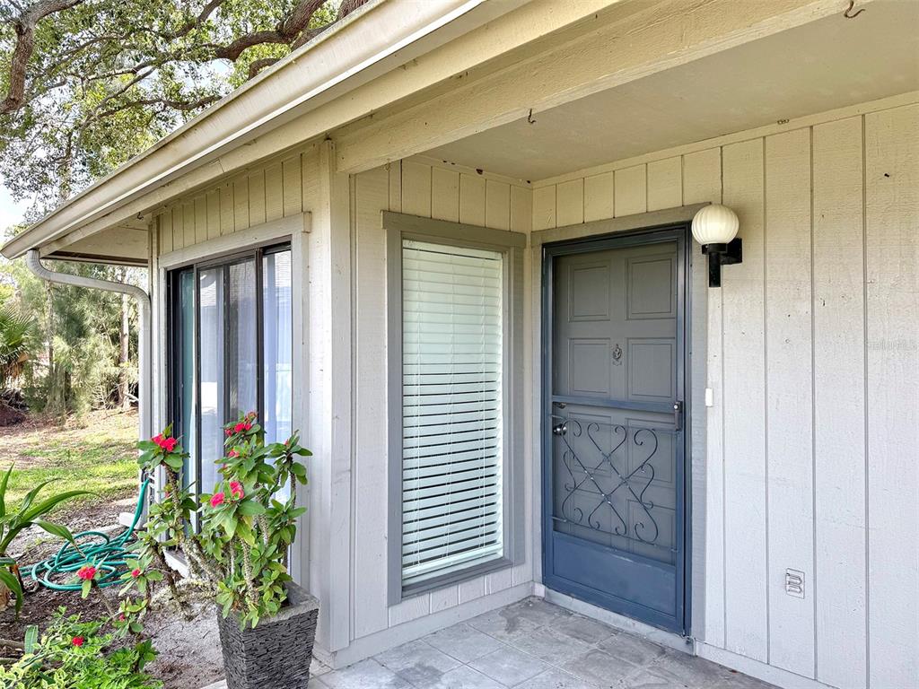 A gray front door with a decorative screen sits beside a window on a porch — 942 N BENEVA ROAD UNIT V28, SARASOTA, FL