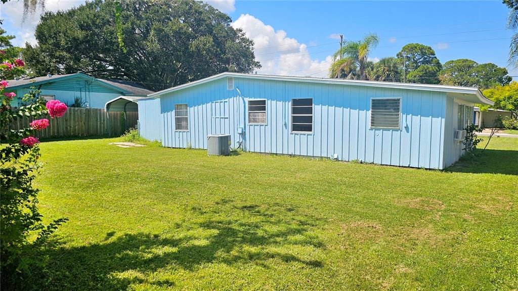 A light blue single-story house with vertical siding sits on a grassy lawn — 903 CONRAD DRIVE, NEW SMYRNA BEACH, FL
