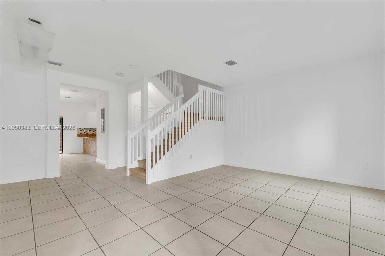 A living area with light tile flooring features a white staircase with wooden steps — 582 NE 207th St, Miami FL 33179, MIAMI, FL