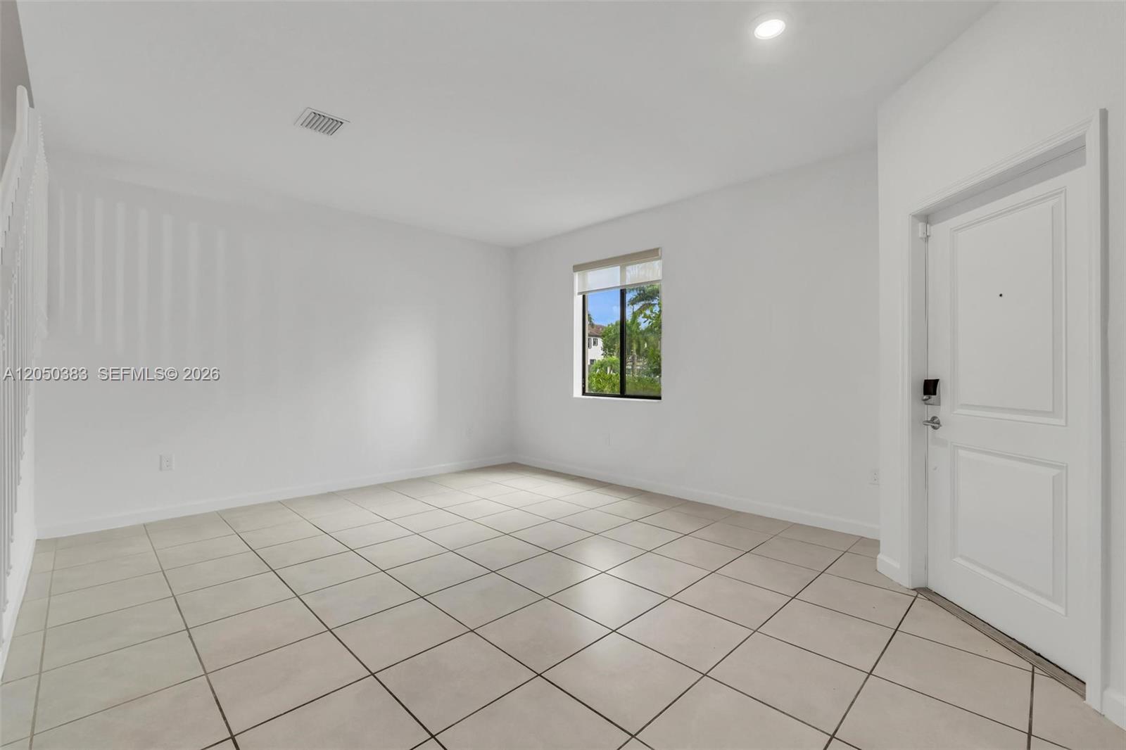 An empty room features white walls, light-colored tile flooring, a single window, and a door — 582 NE 207th St, Miami FL 33179, MIAMI, FL
