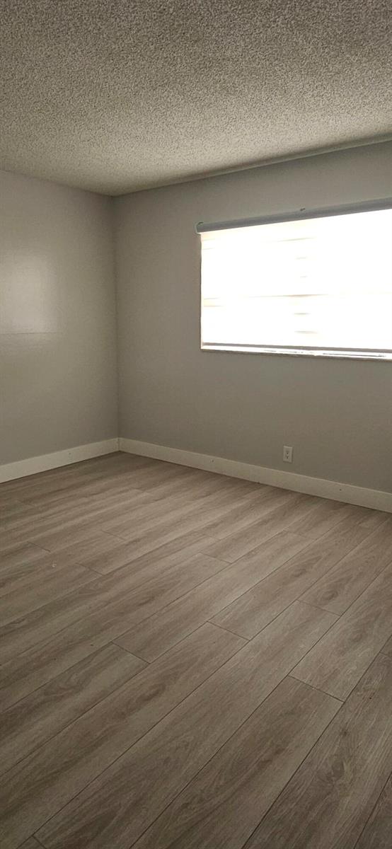 An empty room with light gray walls, wood-look flooring, and a window with blinds — 421 NE 14th Avenue # 302, Hallandale Beach FL 33009, HALLANDALE BEACH, FL