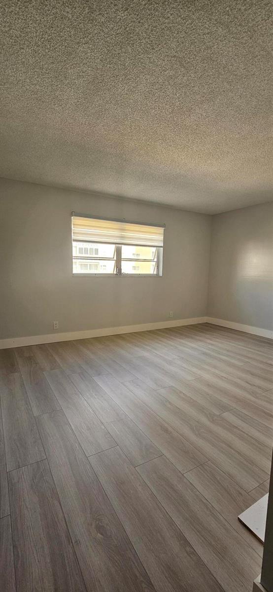 An empty room with light gray walls, wood-look flooring, and a window with blinds — 421 NE 14th Avenue # 302, Hallandale Beach FL 33009, HALLANDALE BEACH, FL