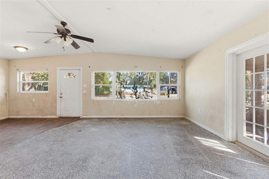 An interior view of a room with a ceiling fan, large windows, and a door — 762 VALENCIA AVENUE, ORANGE CITY, FL