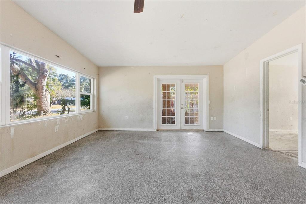 An empty room with light walls, a speckled concrete floor, large windows, and French doors — 762 VALENCIA AVENUE, ORANGE CITY, FL
