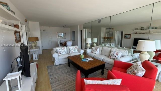 A living room features a white sofa, two red armchairs, and a large mirrored wall — 5161 Collins Ave # 1702, Miami Beach FL 33140, MIAMI BEACH, FL