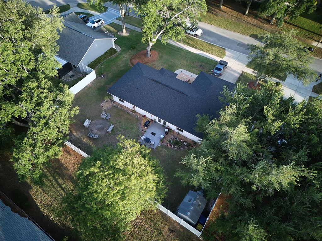An aerial view shows a house with a dark roof, a backyard patio, and trees — 408 RAYMOND STREET, MINNEOLA, FL