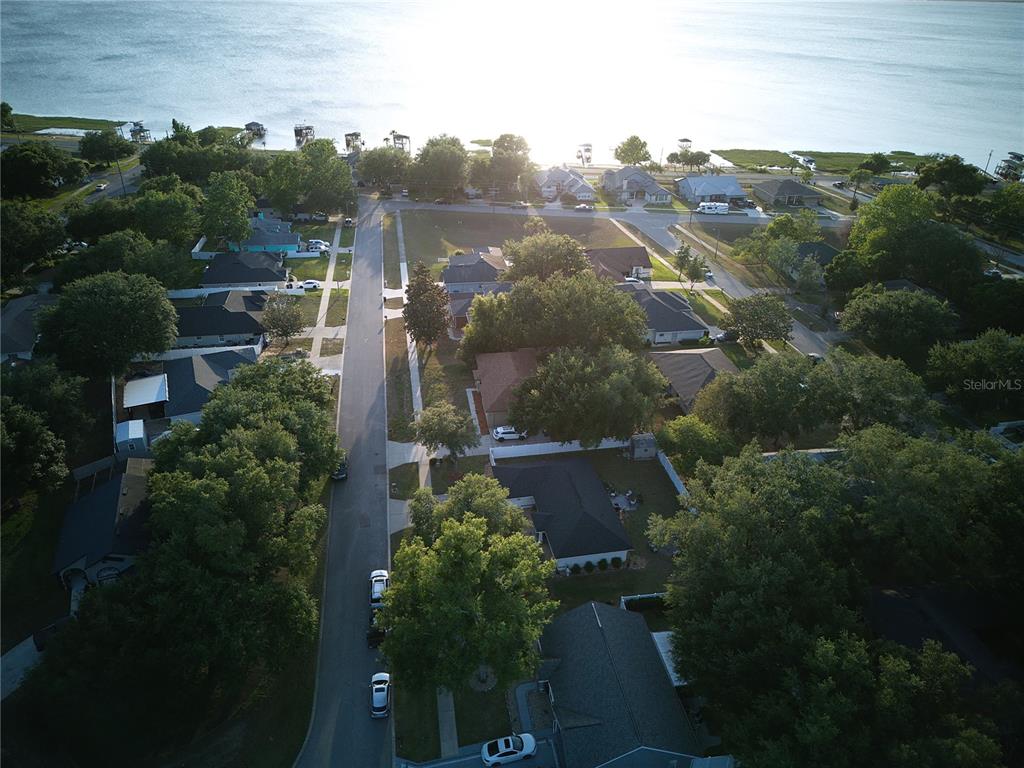 An aerial view shows a residential neighborhood with houses, trees, and a nearby lake — 408 RAYMOND STREET, MINNEOLA, FL