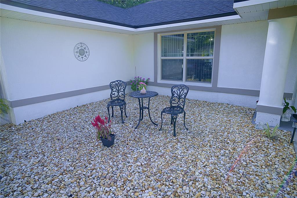 A small patio area features a gravel ground, a metal bistro set, and a window — 408 RAYMOND STREET, MINNEOLA, FL