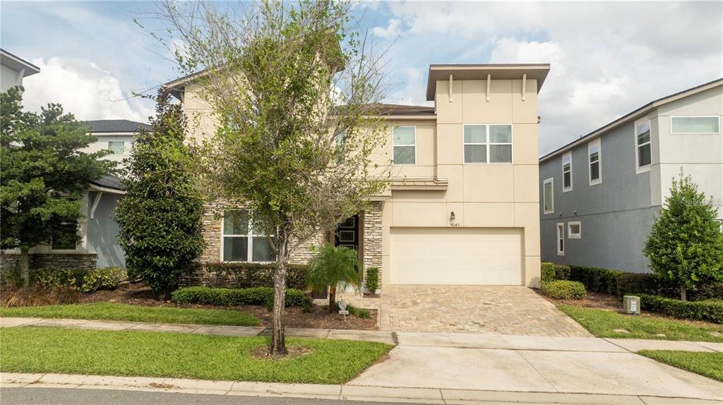 A two-story suburban house with a stone facade, beige stucco, and a two-car garage — 9043 SUNSHINE RIDGE LOOP, KISSIMMEE, FL