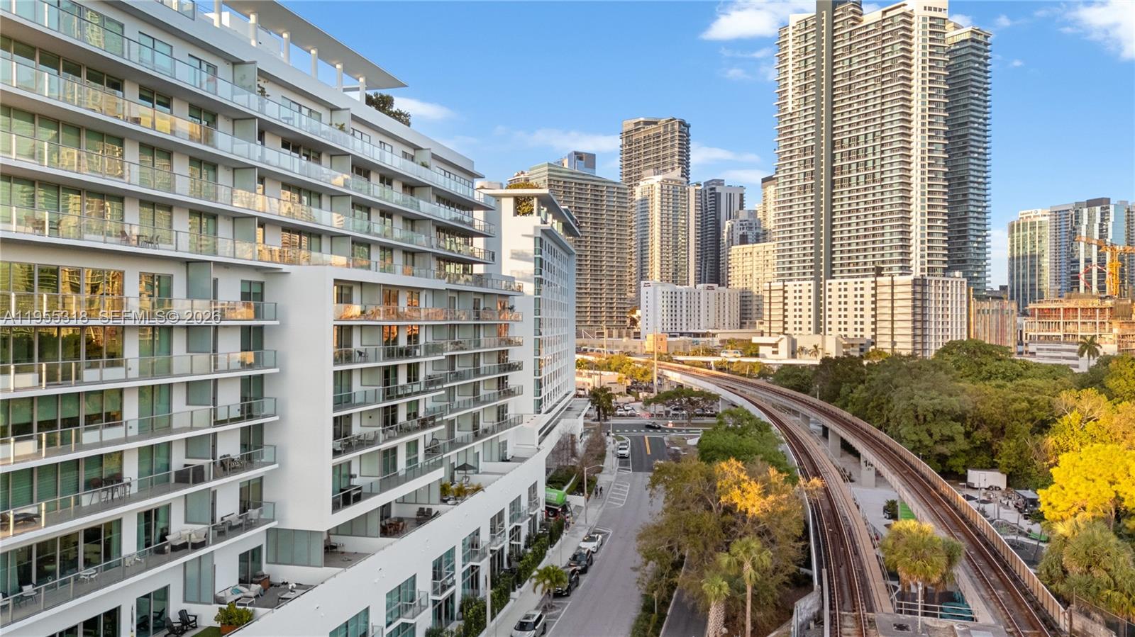 An exterior view shows a modern white apartment building next to elevated train tracks — 1600 SW 1st Ave # 307, Miami FL 33129, MIAMI, FL