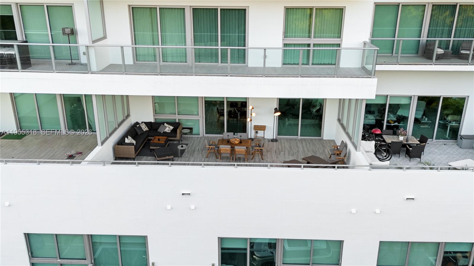 An aerial view shows a large, furnished outdoor balcony with seating and dining areas — 1600 SW 1st Ave # 307, Miami FL 33129, MIAMI, FL
