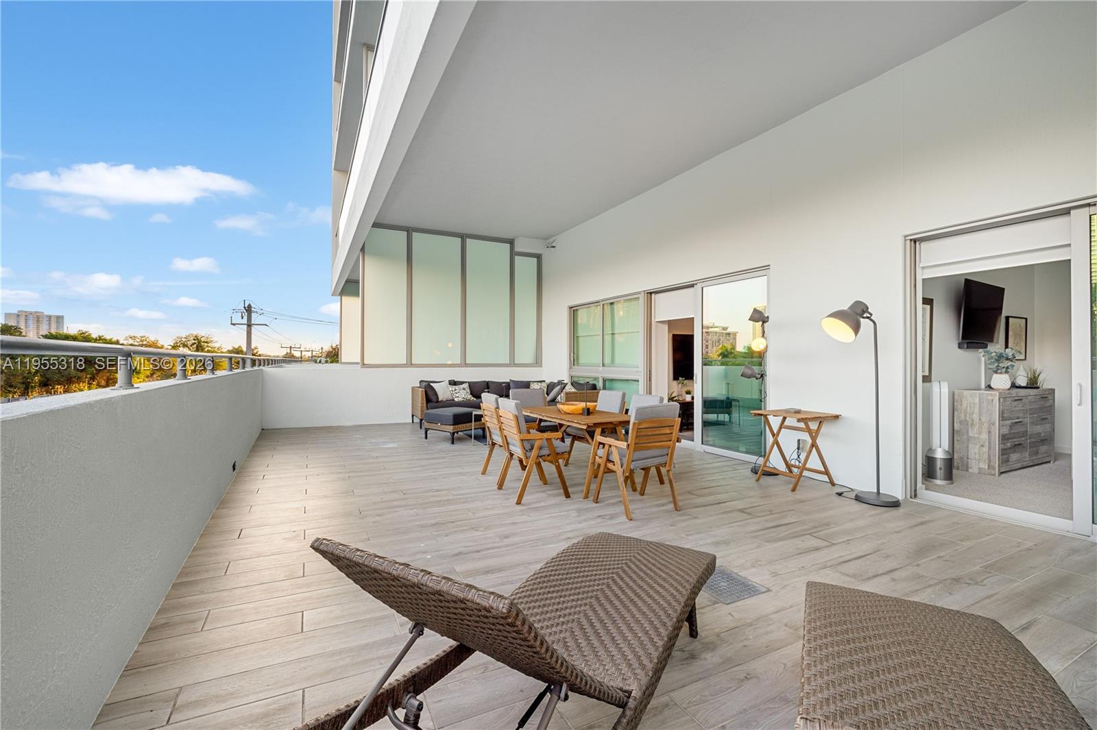 A spacious outdoor balcony features wood-look tile flooring, patio furniture, and a floor lamp — 1600 SW 1st Ave # 307, Miami FL 33129, MIAMI, FL