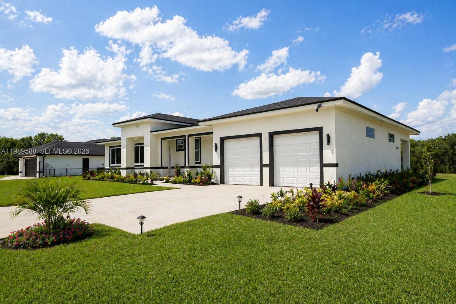 A modern single-story house with a two-car garage, white stucco walls, and black trim — 1715 McArthur Ave, Lehigh Acres FL 33972, LEHIGH ACRES, FL