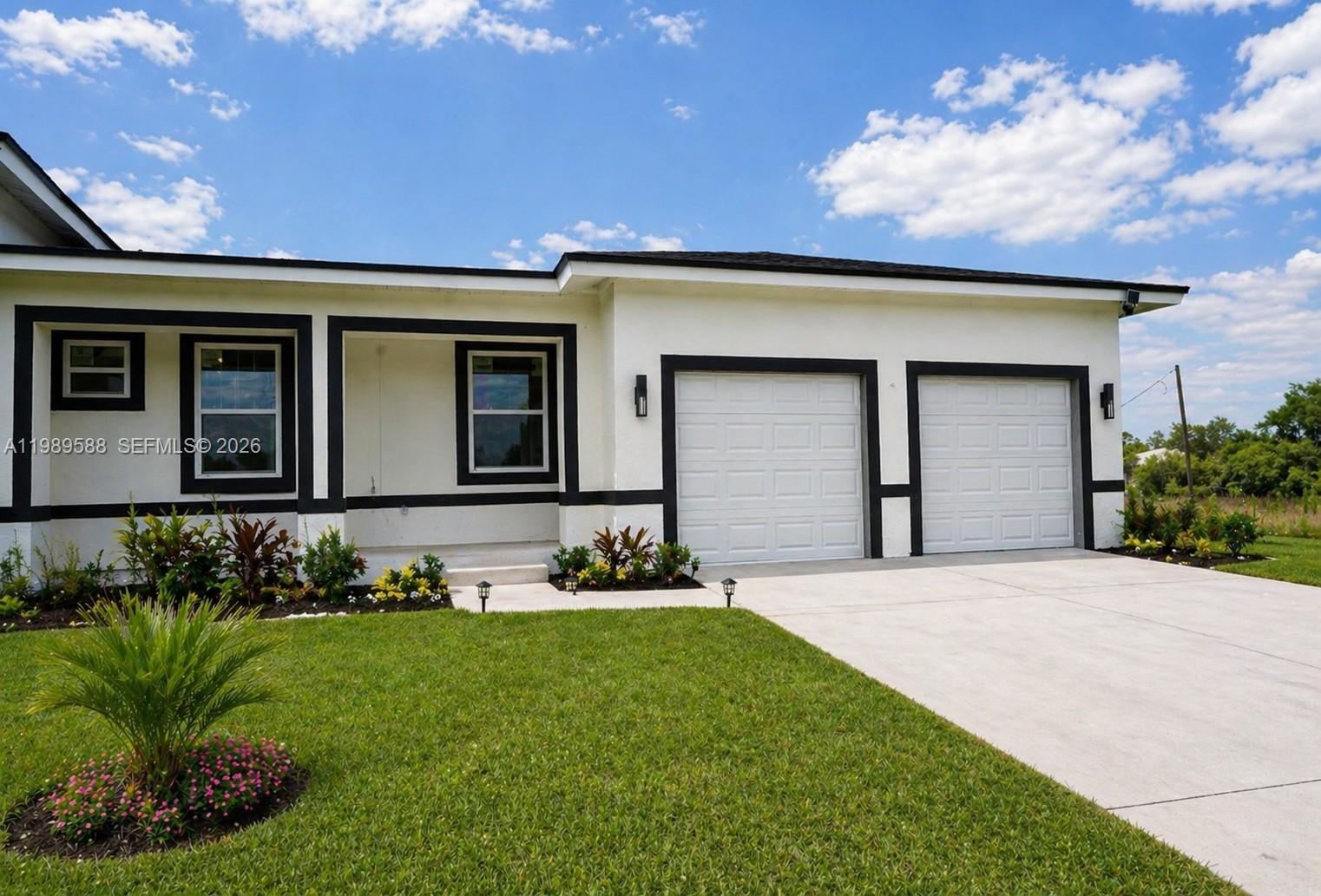 A single-story house with a white exterior, black trim, and a two-car garage — 1715 McArthur Ave, Lehigh Acres FL 33972, LEHIGH ACRES, FL