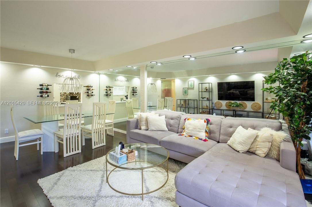 A living and dining room features a grey sectional sofa, glass tables, and mirrored walls — 7100 Nova Dr # 104A, Davie FL 33317, DAVIE, FL