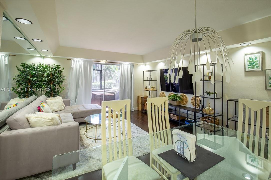 A living and dining area features a sectional sofa, glass table, and modern chandelier — 7100 Nova Dr # 104A, Davie FL 33317, DAVIE, FL