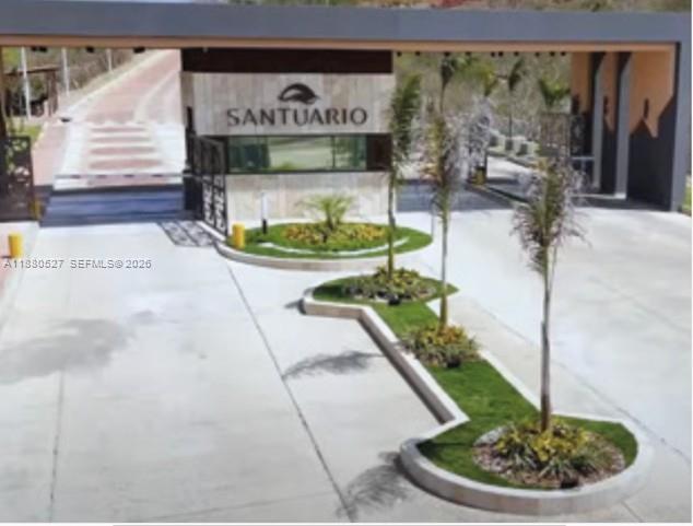 A gated entrance with a stone sign reading Santuario and landscaped palm tree islands — 3 el santuario, ba, ba