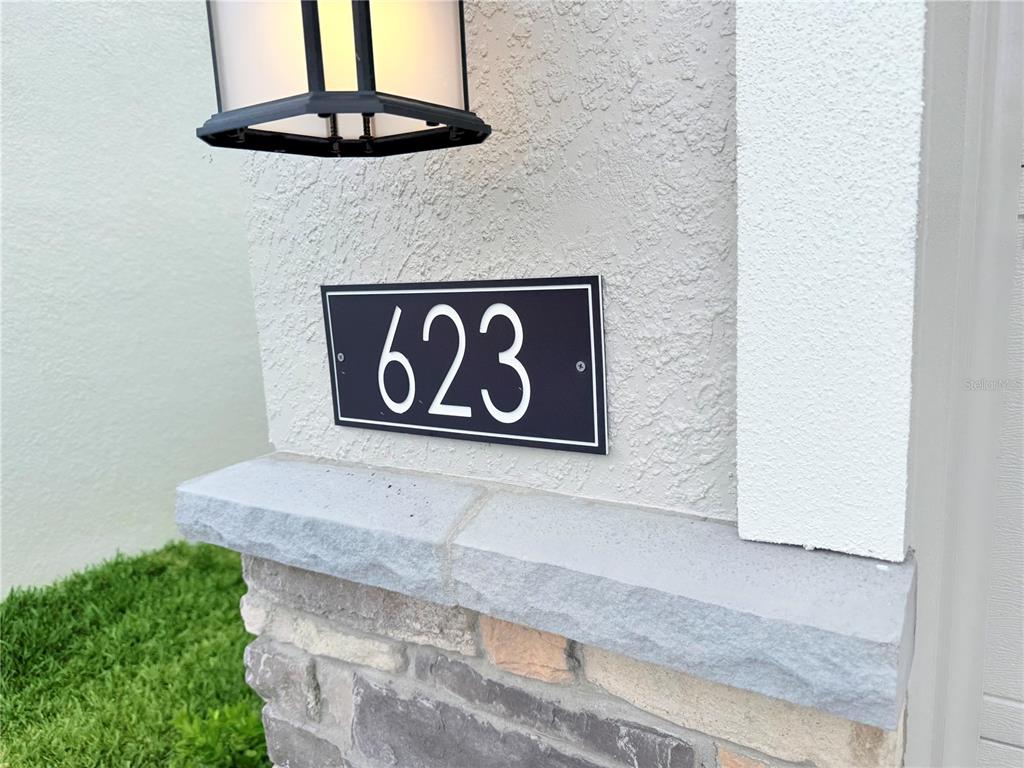 A black address plaque with the number 623 is mounted on a textured exterior wall — 623 TERRAPIN DRIVE, DEBARY, FL
