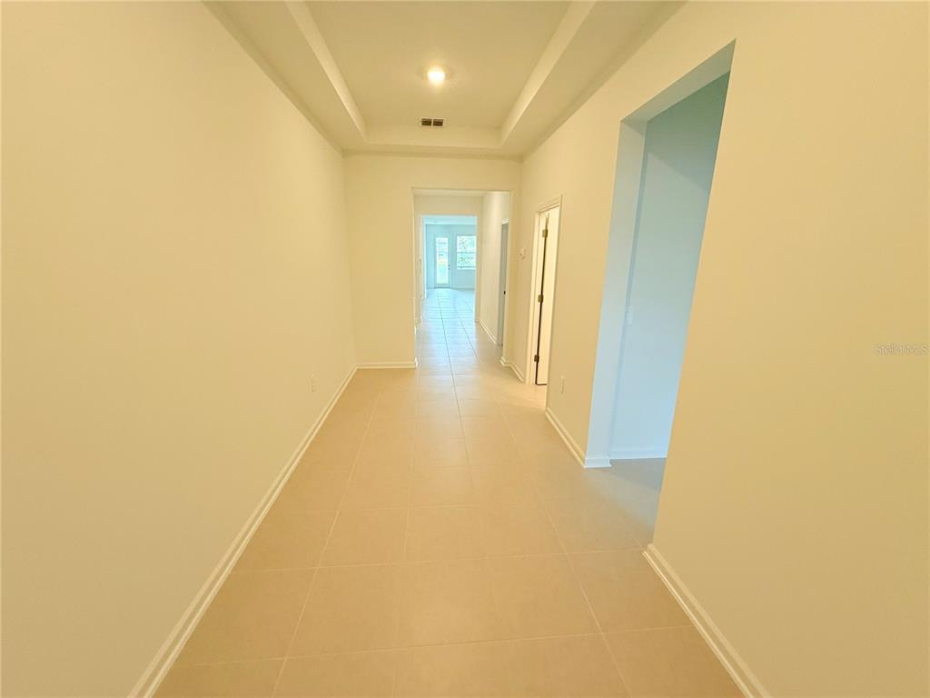 A long, tiled hallway leads to a doorway with a view of the outdoors — 623 TERRAPIN DRIVE, DEBARY, FL