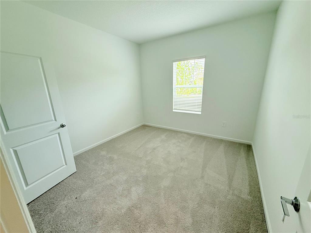 An empty bedroom features white walls, gray carpeting, and a single window with blinds — 623 TERRAPIN DRIVE, DEBARY, FL