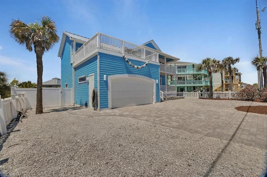 A blue two-story house with a white garage door and a gravel driveway — 6344 S ATLANTIC AVENUE, NEW SMYRNA BEACH, FL
