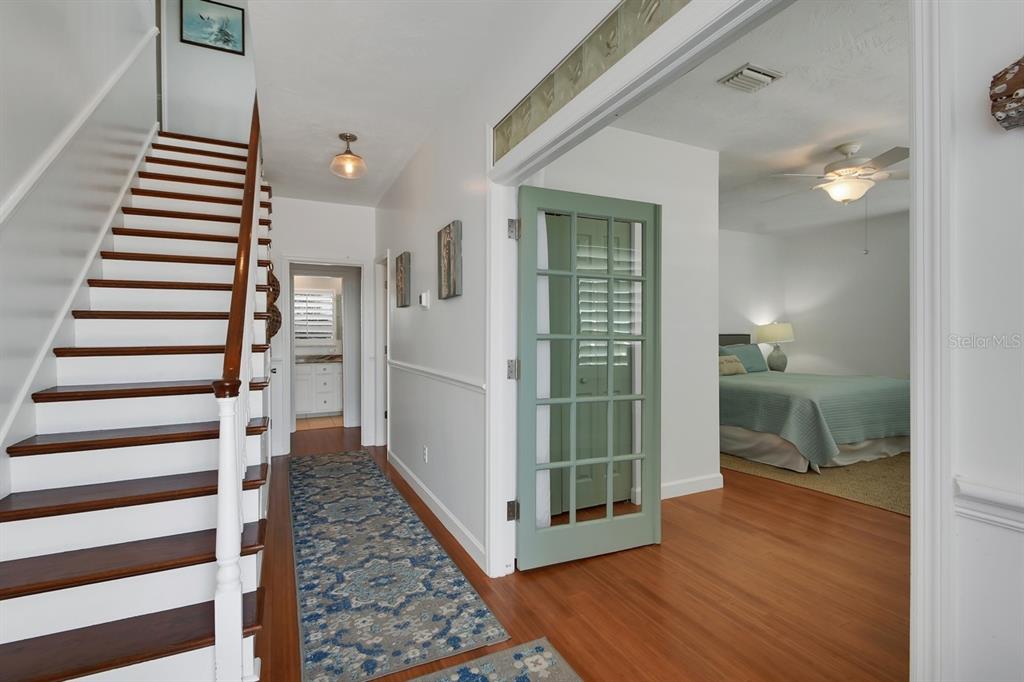 A hallway with a wooden staircase leads to a bedroom through a green glass door — 6344 S ATLANTIC AVENUE, NEW SMYRNA BEACH, FL