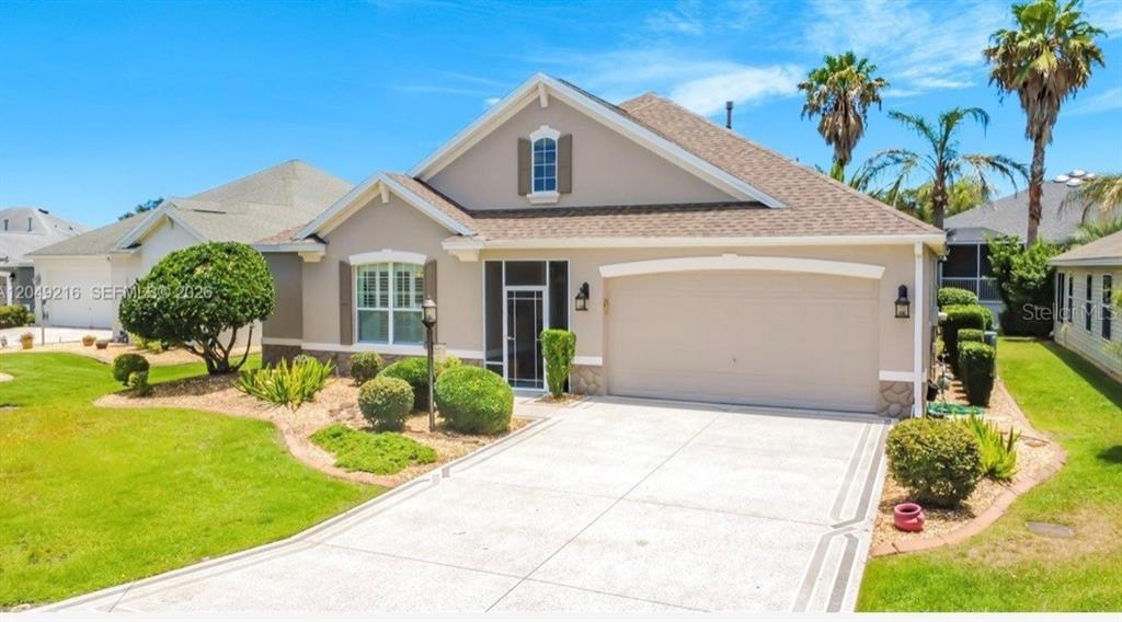 The exterior of a beige single-story house features a two-car garage and a landscaped yard — 1637 WESTMINSTER COURT, THE VILLAGES, FL