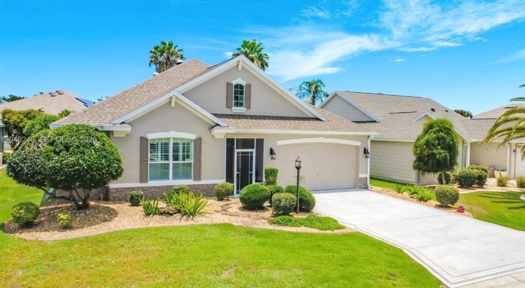 A single-story house with a beige exterior, stone accents, and a concrete driveway — 1637 WESTMINSTER COURT, THE VILLAGES, FL