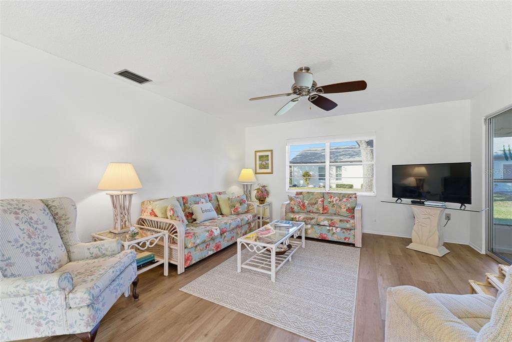 A living room features floral sofas, a glass coffee table, and light wood-look flooring — 605 APPLE LANE, ENGLEWOOD, FL